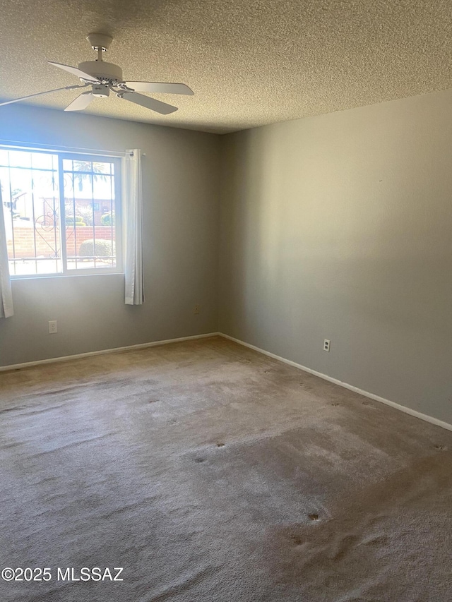 empty room featuring carpet floors, a ceiling fan, baseboards, and a textured ceiling