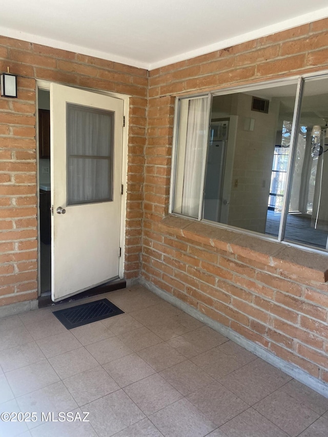 doorway to property with visible vents and brick siding