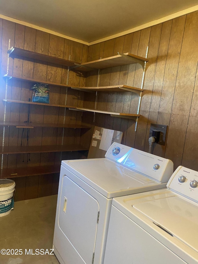 laundry room featuring laundry area, wood walls, and washing machine and clothes dryer