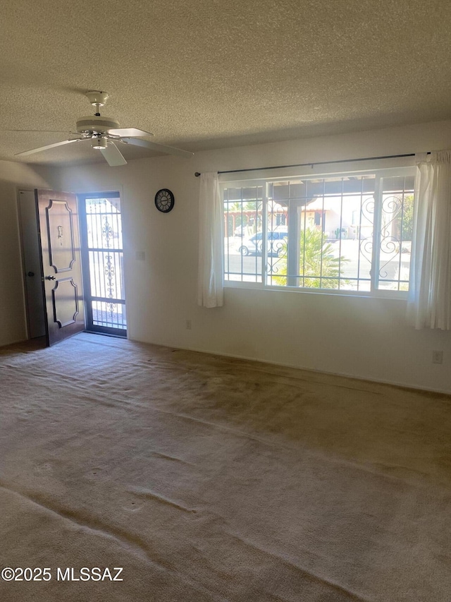 unfurnished room with a ceiling fan, carpet, and a textured ceiling