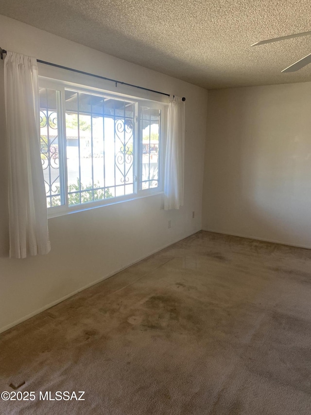 carpeted spare room featuring ceiling fan and a textured ceiling