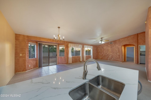 kitchen featuring light stone countertops, ceiling fan with notable chandelier, sink, pendant lighting, and light tile patterned floors