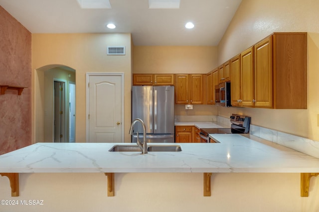 kitchen with sink, light stone countertops, a kitchen bar, kitchen peninsula, and stainless steel appliances