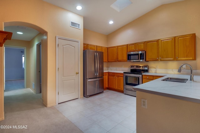 kitchen with light carpet, light stone countertops, stainless steel appliances, sink, and high vaulted ceiling