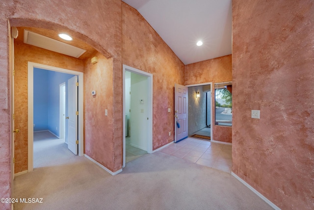 hall featuring high vaulted ceiling and light colored carpet