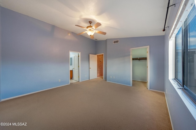 unfurnished bedroom featuring a walk in closet, ceiling fan, connected bathroom, light colored carpet, and a closet