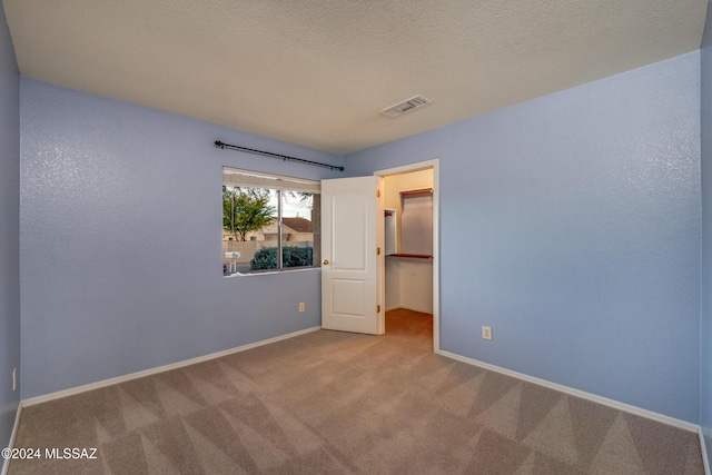 unfurnished bedroom with light colored carpet, a spacious closet, and a closet