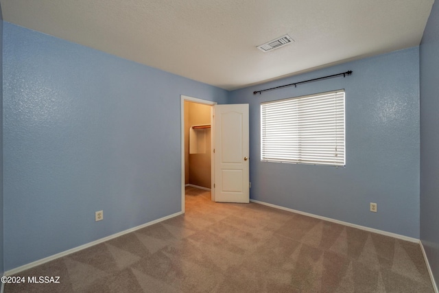 unfurnished bedroom with light colored carpet, a spacious closet, and a closet