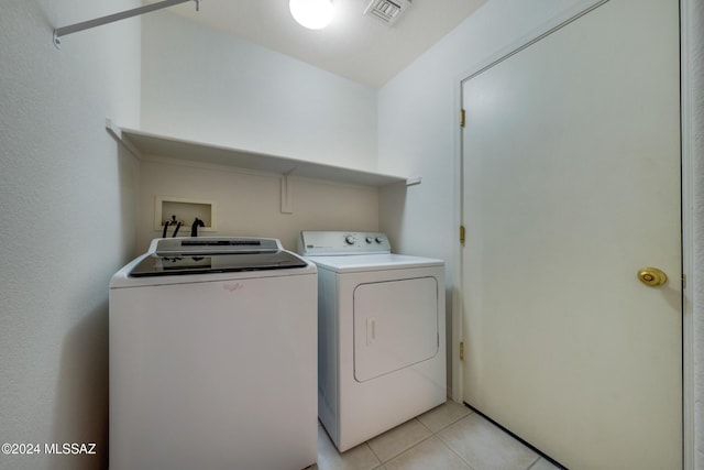 laundry room featuring washing machine and dryer and light tile patterned flooring