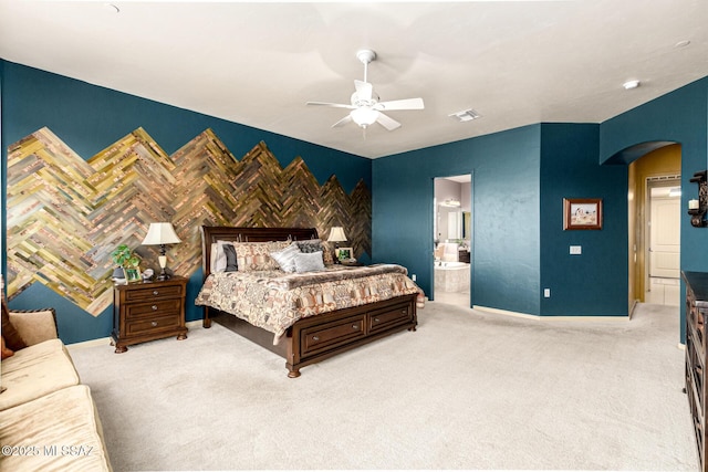 bedroom featuring ceiling fan, light carpet, and ensuite bath