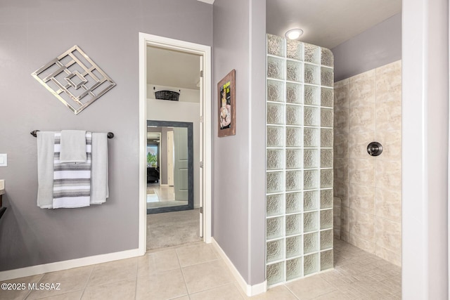 bathroom featuring tile patterned flooring, vanity, and a tile shower