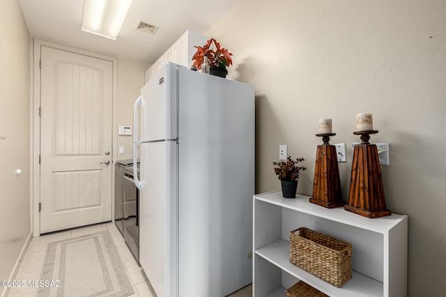 kitchen featuring white cabinetry, light tile patterned flooring, and white fridge