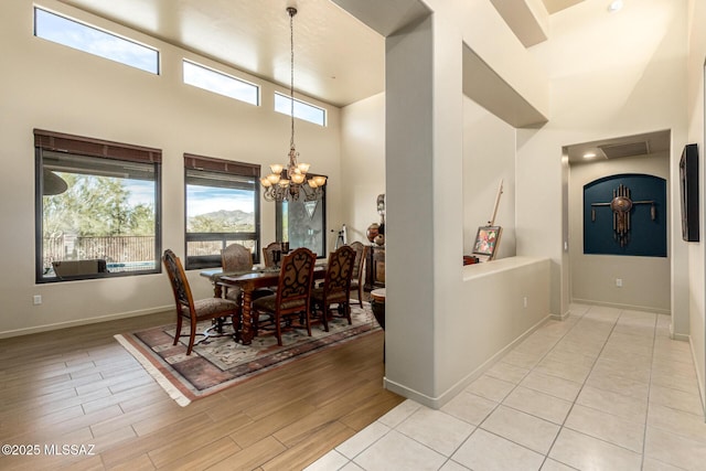 dining space featuring light hardwood / wood-style flooring, a chandelier, and a high ceiling