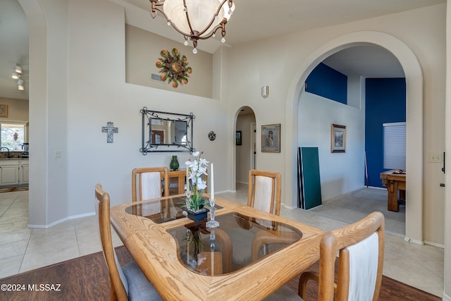 tiled dining room with billiards, a high ceiling, and an inviting chandelier