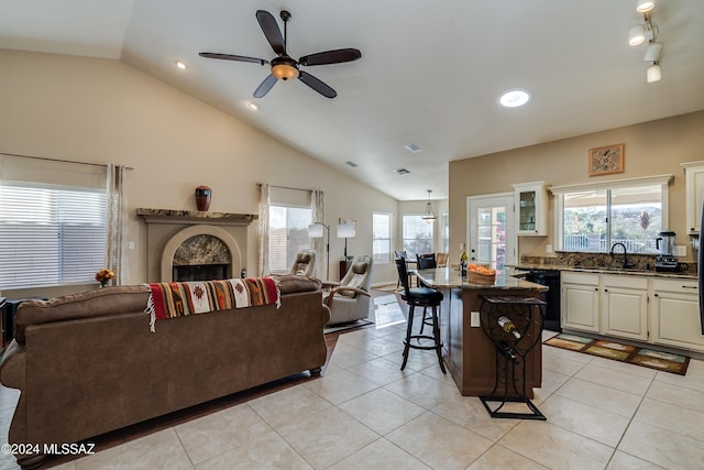 tiled living room featuring plenty of natural light, sink, ceiling fan with notable chandelier, and vaulted ceiling