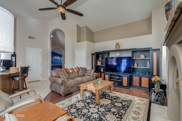 tiled living room with ceiling fan and a high ceiling