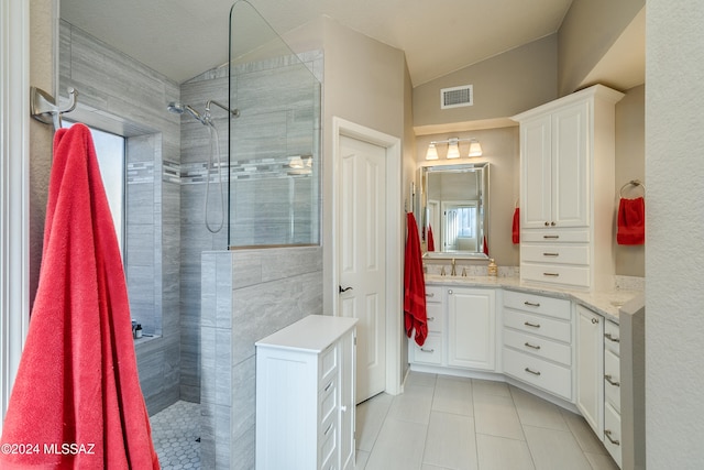 bathroom featuring a wealth of natural light, vanity, tiled shower, tile patterned flooring, and lofted ceiling