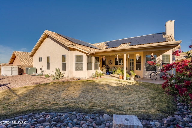 back of property featuring a lawn, central AC, a patio, and solar panels