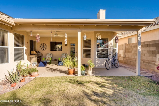 rear view of property with a yard, a patio, and ceiling fan