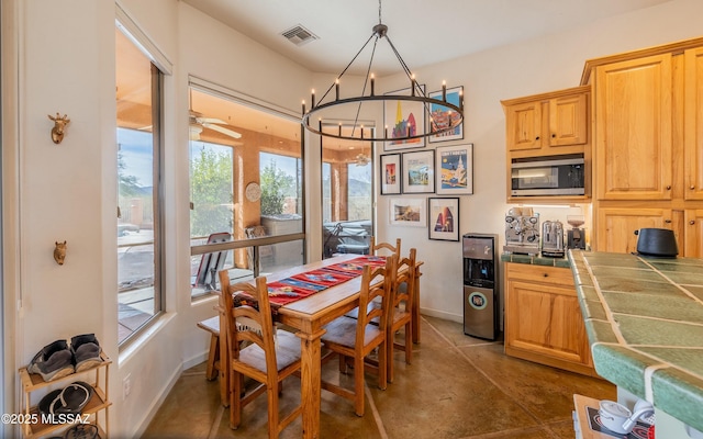 dining area with visible vents, baseboards, and ceiling fan with notable chandelier