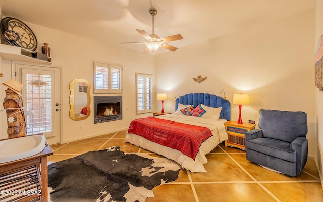 tiled bedroom featuring a ceiling fan, a glass covered fireplace, and access to outside