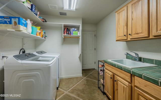 laundry area with washing machine and dryer, cabinet space, a sink, and visible vents