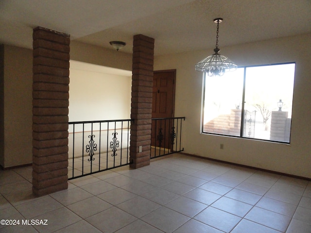 spare room featuring light tile patterned floors and ornate columns