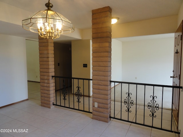 hall with light tile patterned floors, decorative columns, and a notable chandelier