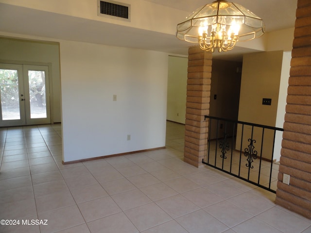 tiled spare room with french doors and a chandelier