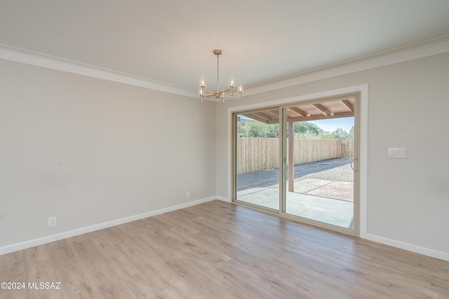 empty room with ornamental molding, light hardwood / wood-style floors, and a chandelier