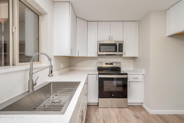 kitchen featuring white cabinetry, appliances with stainless steel finishes, sink, and light wood-type flooring