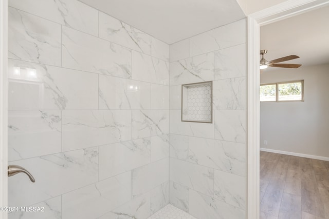 bathroom with a tile shower, wood-type flooring, and ceiling fan