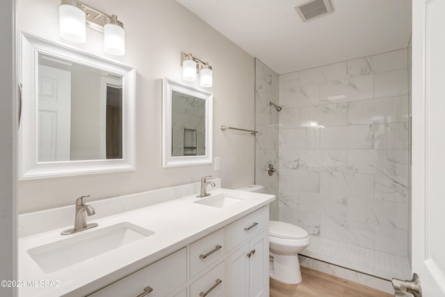 bathroom with vanity, hardwood / wood-style flooring, toilet, and tiled shower