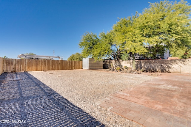 view of yard with a storage shed and a patio