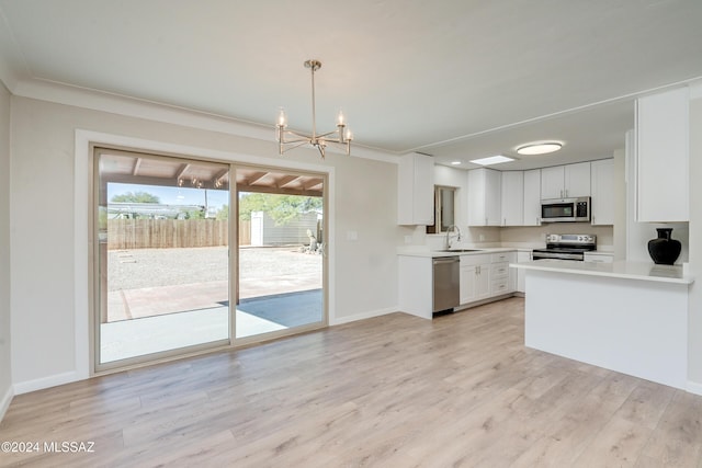 kitchen with pendant lighting, sink, white cabinets, stainless steel appliances, and light hardwood / wood-style flooring