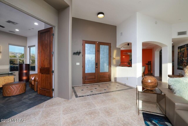 tiled entrance foyer with arched walkways, visible vents, recessed lighting, and french doors