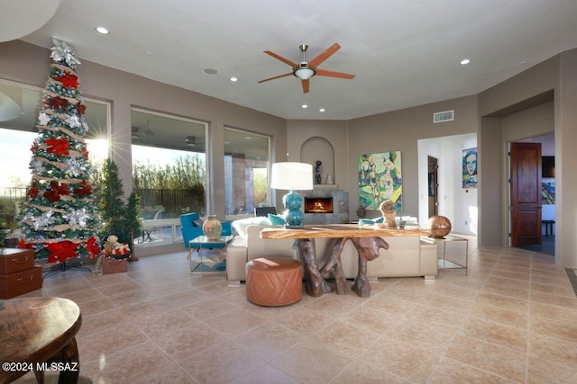 living area with recessed lighting, visible vents, a lit fireplace, and a ceiling fan