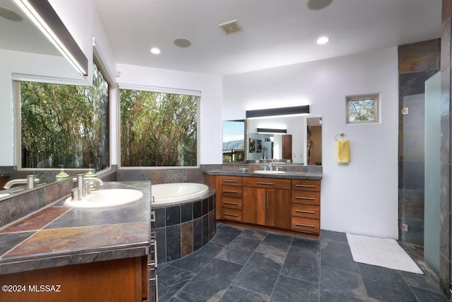 bathroom with stone finish floor, a bath, visible vents, and a sink