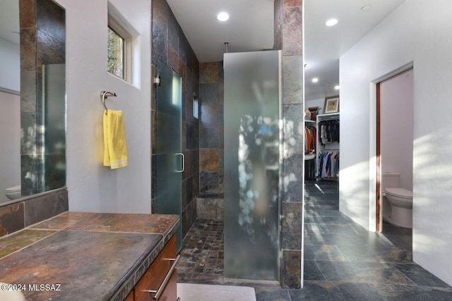 bathroom with stone finish floor, toilet, recessed lighting, and a stall shower