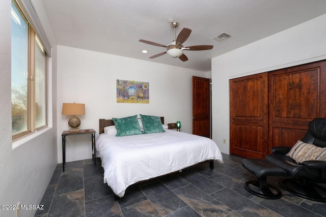 bedroom with a closet, visible vents, stone finish flooring, and a ceiling fan