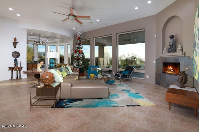 living room with ceiling fan with notable chandelier, light tile patterned flooring, and a fireplace