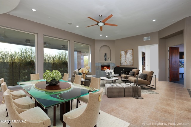 living area with light tile patterned floors, a ceiling fan, visible vents, recessed lighting, and a lit fireplace