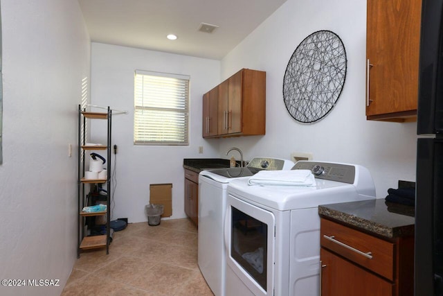 laundry area featuring washing machine and clothes dryer, light tile patterned floors, and cabinets