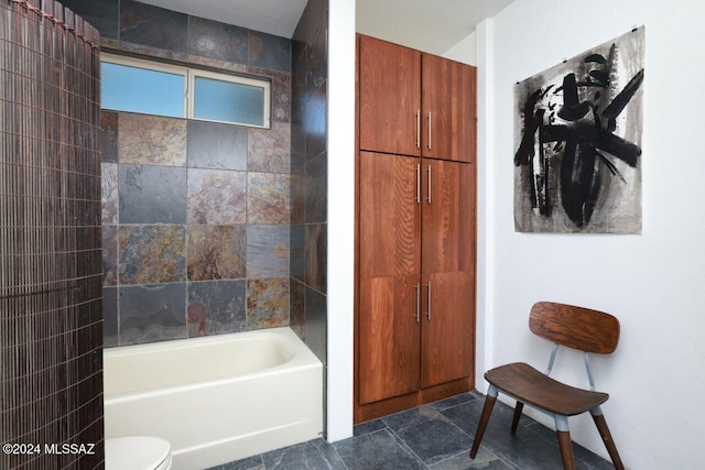 full bathroom featuring stone finish floor, toilet, and shower / bathtub combination