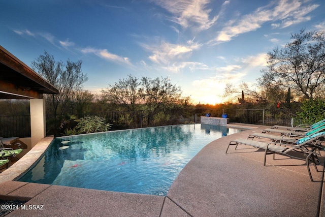 pool at dusk with a patio area