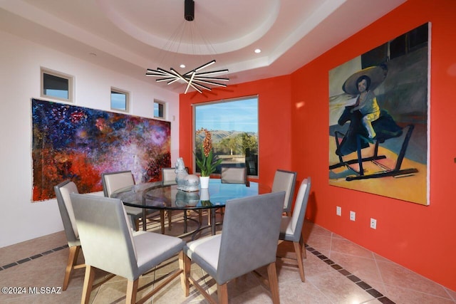 dining area with tile patterned flooring, a tray ceiling, and a notable chandelier