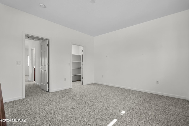 unfurnished bedroom featuring a spacious closet, carpet floors, and a closet