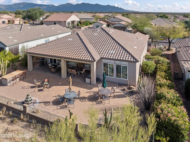 rear view of property with a mountain view and a patio area