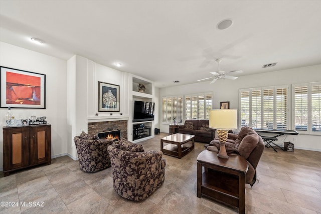 living room featuring a stone fireplace, ceiling fan, and built in features