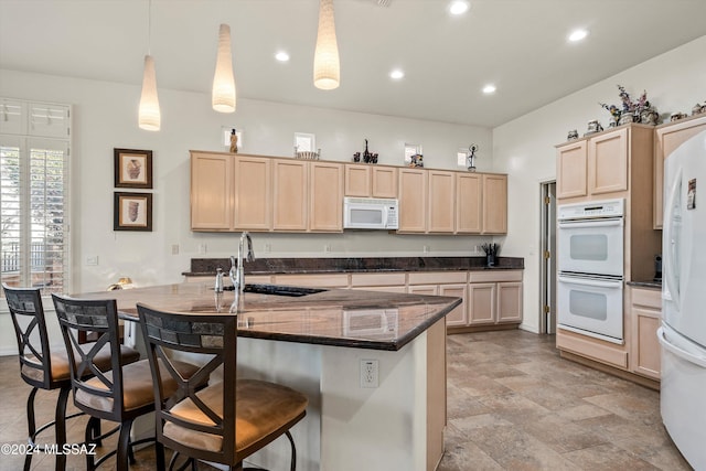 kitchen with light brown cabinets, sink, hanging light fixtures, white appliances, and a breakfast bar area